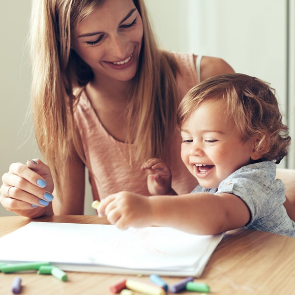 Photo of a woman with a little girl sitting next to her and showing something on the table