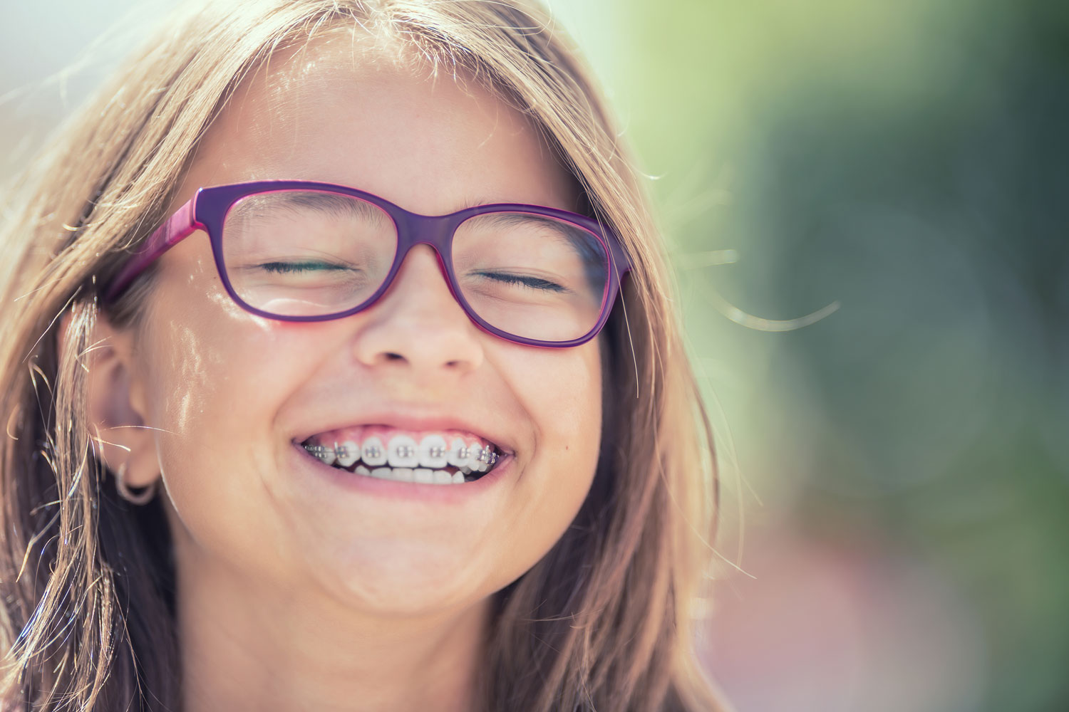 A photo of a smiling little girl with braces on her teeth